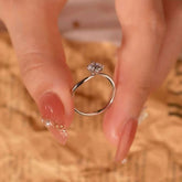 Artistic bypass solitaire ring held between fingers, showing the elegant curved band